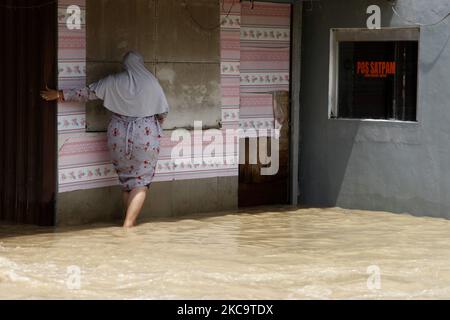 Bewohner, die am 22. Februar 2021 die Überschwemmungen im Teilbezirk Pebayuran, Bekasi-Regentschaft, West-Java, überquerten. Massive Überschwemmungen trafen eine Reihe von Dörfern in Bekasi Regentschaft, West-Java, nach starken Regenfällen, die in den letzten Tagen auftraten und einen Überlauf des Flusses Cibeet verursachten und den Citarum-Damm platzten. Mindestens 6,000 Familien waren von dieser Katastrophe betroffen. (Foto von Aditya Irawan/NurPhoto) Stockfoto