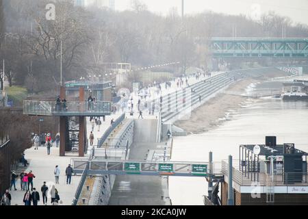 Am 25. Februar 2021 werden Menschen auf dem Boulevard der Weichsel in Warschau, Polen, spazieren gesehen. Die Regierung kündigte am Donnerstag eine Änderung der Regeln an, die die Verwendung jeglicher Art von Gesichtsbedeckung, die keine richtige Gesichtsmaske ist, verbieten wird. Während die Temperaturen weit über 10 Grad Celsius erreichten, versammeln sich viele im Freien ohne Masken entlang der Flussufer. (Foto von Jaap Arriens/NurPhoto) Stockfoto