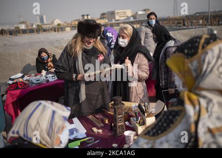 Zwei iranische Frauen, die eine von ihnen mit einer schützenden Gesichtsmaske tragen, schauen sich während des Einkaufens im Parvaneh Friday-Bazaar (Markt) in Zentral-Teheran während des Ausbruchs der neuen Coronavirus-Krankheit (COVID-19) im Iran am 26. Februar 2021 Waren an. Die iranischen Beamten haben die Menschen gewarnt, dass sich das Land am Rande der vierten Welle des COVID-19-Ausbruchs befindet und es wird passieren, dass die Menschen keine Gesundheitsprotokolle, keine soziale Distanzierung und keine Reisen in die anderen Städte mehr halten. (Foto von Morteza Nikoubazl/NurPhoto) Stockfoto