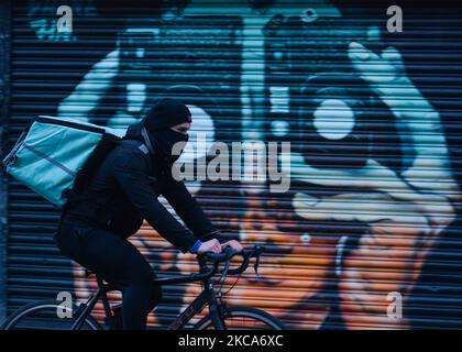 Ein Mann, der eine Gesichtsmaske trägt, radelt während der Covid-19-Sperre auf Ebene 5 durch einen geschlossenen Laden im Stadtzentrum von Dublin. Am Montag, den 1. März 2021, in Dublin, Irland. (Foto von Artur Widak/NurPhoto) Stockfoto