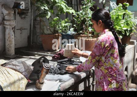 Jain Woman bereitet ein kohlebetriebenes Bügeleisen vor, bevor sie ihre Kleidung außerhalb ihres Hauses in Alt-Delhi, Indien, bügelt. (Foto von Creative Touch Imaging Ltd./NurPhoto) Stockfoto