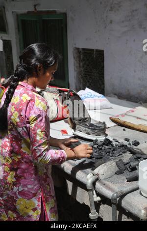 Jain Woman bereitet ein kohlebetriebenes Bügeleisen vor, bevor sie ihre Kleidung außerhalb ihres Hauses in Alt-Delhi, Indien, bügelt. (Foto von Creative Touch Imaging Ltd./NurPhoto) Stockfoto