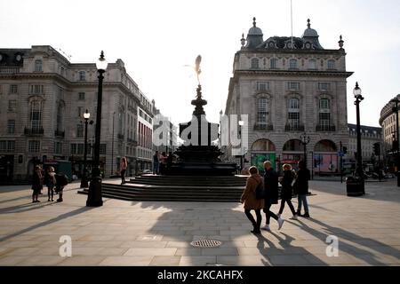 Am 8. März 2021 laufen Menschen durch einen fast menschenleeren Piccadilly Circus in London, England. Heute war die erste Phase der Lockerung des Coronavirus in ganz England, mit der Wiedereröffnung der Schulen und einer Lockerung einiger Grenzen für den sozialen Kontakt. Geschäfte, Bars, Restaurants und andere Gaststätten, die nicht unbedingt notwendig sind, bleiben jedoch geschlossen und werden nach dem aktuellen Zeitplan erst im nächsten Monat wieder eröffnet. (Foto von David Cliff/NurPhoto) Stockfoto