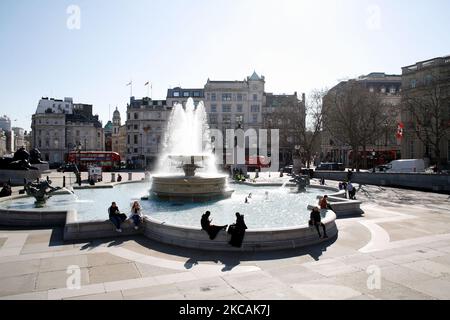 Am 9. März 2021 sitzen Menschen bei mildem Frühlingswetter in London, England, an einem der Brunnen eines fast menschenleeren Trafalgar Square. Gestern war die erste Phase der Lockerung des Coronavirus in ganz England, mit der Wiedereröffnung der Schulen und einer Lockerung einiger Grenzen für den sozialen Kontakt. Geschäfte, Bars, Restaurants und andere Gaststätten, die nicht unbedingt notwendig sind, bleiben jedoch geschlossen und werden nach dem aktuellen Zeitplan erst im nächsten Monat wieder eröffnet. (Foto von David Cliff/NurPhoto) Stockfoto