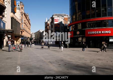 Am 9. März 2021 laufen Menschen durch einen fast menschenleeren Leicester Square in London, England. Gestern war die erste Phase der Lockerung des Coronavirus in ganz England, mit der Wiedereröffnung der Schulen und einer Lockerung einiger Grenzen für den sozialen Kontakt. Geschäfte, Bars, Restaurants und andere Gaststätten, die nicht unbedingt notwendig sind, bleiben jedoch geschlossen und werden nach dem aktuellen Zeitplan erst im nächsten Monat wieder eröffnet. (Foto von David Cliff/NurPhoto) Stockfoto