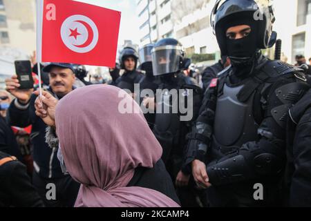 Eine Protesterin islamistischer Bewegungen hebt die Flagge Tunesiens vor den Sicherheitskräften, während einer Demonstration vor dem Hauptquartier der tunesischen Niederlassung der Internationalen Union für muslimische Gelehrte (IUMS) in der Hauptstadt Tunis, Tunesien, am 10. März 2021, Aus Protest gegen den Präsidenten der Freien Destourien Partei (PDL), Abir Moussi und ihre Anhänger, die vor dem Hauptquartier der IUL ein Sit-in abhalten, um ihre Auflösung zu fordern. (Foto von Chedly Ben Ibrahim/NurPhoto) Stockfoto