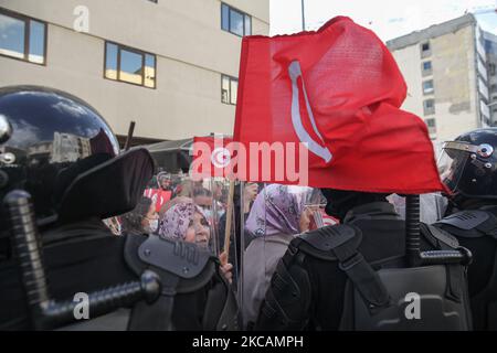 Eine Protesterin islamistischer Bewegungen steht vor den Sicherheitskräften, während sie die tunesische Flagge hebt, während einer Demonstration vor dem Hauptquartier der tunesischen Niederlassung der Internationalen Union für muslimische Gelehrte (IUMS) in der Hauptstadt Tunis, Tunesien, am 10. März 2021, Aus Protest gegen den Präsidenten der Freien Destourien Partei (PDL), Abir Moussi und ihre Anhänger, die vor dem Hauptquartier der IUL ein Sit-in abhalten, um ihre Auflösung zu fordern. (Foto von Chedly Ben Ibrahim/NurPhoto) Stockfoto