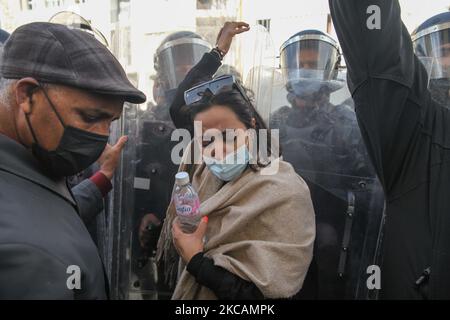 Während einer Demonstration vor dem Hauptsitz der tunesischen Zweigstelle der Internationalen Union für muslimische Gelehrte (IUMS) in der Hauptstadt Tunis, Tunesien, am 10. März 2021, steht eine Protesterin islamistischer Bewegungen an vorderster Front von Sicherheitskräften, die Schilde halten. Aus Protest gegen den Präsidenten der Freien Destourien Partei (PDL), Abir Moussi und ihre Anhänger, die vor dem Hauptquartier der IUL ein Sit-in abhalten, um ihre Auflösung zu fordern. (Foto von Chedly Ben Ibrahim/NurPhoto) Stockfoto