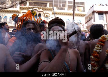 Ein Naga Sadhu oder heiliger Mann von Juna Akhara raucht Unkraut, während andere sich in Richtung ganges-Fluss bewegen, um während des Maha Kumbh Festivals, in Haridwar am 11. März 2021, ein heiliges Bad zu nehmen. (Foto von Ritesh Shukla/NurPhoto) Stockfoto