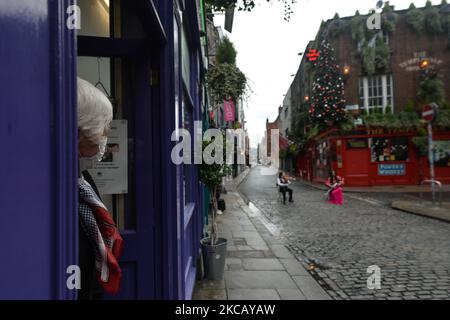 Ein örtlicher Apotheker beobachtet Musiker vor der Temple Bar. Genau ein Jahr seit der Schließung des Viertels Temple Bar aufgrund der COVID-19-Pandemie beklagt sich der weltbekannte Geiger Frankie Gavin im verlassenen Kulturviertel von Dublin. Zu ihm gesellt sich die Pfeiferin Louise Mulcahy. Am Montag, den 15. März 2021, in Dublin, Irland. (Foto von Artur Widak/NurPhoto) Stockfoto