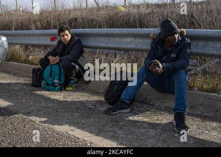 Auf der Autobahn in der Nähe der Stadt Orestiada in der Region Evros, Thrakien, in Griechenland, befinden sich Polizeiautos und Polizeibeamte, die 2 Migranten ohne Papiere halten, einen aus Afghanistan und einen aus Afrika, die illegal die Grenzen der Türkei überquerten. Der Evros-Fluss oder Martisa oder Meric ist die südöstlichere Außengrenze der EU und des Schengen-Raums. Asylbewerber werden entlang der griechisch-türkischen Grenzen gefangen genommen, während sie versuchen, nach Griechenland und in die Europäische Union einzureisen. Die hellenische Polizei und Frontex-Truppen machen die Grenzpatrouille und nehmen täglich fest oder verhaften Migranten, Flüchtlinge und Schmuggler auf den griechischen Stockfoto