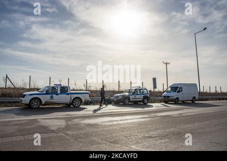 Auf der Autobahn in der Nähe der Stadt Orestiada in der Region Evros, Thrakien, in Griechenland, befinden sich Polizeiautos und Polizeibeamte, die 2 Migranten ohne Papiere halten, einen aus Afghanistan und einen aus Afrika, die illegal die Grenzen der Türkei überquerten. Der Evros-Fluss oder Martisa oder Meric ist die südöstlichere Außengrenze der EU und des Schengen-Raums. Asylbewerber werden entlang der griechisch-türkischen Grenzen gefangen genommen, während sie versuchen, nach Griechenland und in die Europäische Union einzureisen. Die hellenische Polizei und Frontex-Truppen machen die Grenzpatrouille und nehmen täglich fest oder verhaften Migranten, Flüchtlinge und Schmuggler auf den griechischen Stockfoto