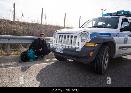 Auf der Autobahn in der Nähe der Stadt Orestiada in der Region Evros, Thrakien, in Griechenland, befinden sich Polizeiautos und Polizeibeamte, die 2 Migranten ohne Papiere halten, einen aus Afghanistan und einen aus Afrika, die illegal die Grenzen der Türkei überquerten. Der Evros-Fluss oder Martisa oder Meric ist die südöstlichere Außengrenze der EU und des Schengen-Raums. Asylbewerber werden entlang der griechisch-türkischen Grenzen gefangen genommen, während sie versuchen, nach Griechenland und in die Europäische Union einzureisen. Die hellenische Polizei und Frontex-Truppen machen die Grenzpatrouille und nehmen täglich fest oder verhaften Migranten, Flüchtlinge und Schmuggler auf den griechischen Stockfoto