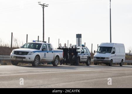 Auf der Autobahn in der Nähe der Stadt Orestiada in der Region Evros, Thrakien, in Griechenland, befinden sich Polizeiautos und Polizeibeamte, die 2 Migranten ohne Papiere halten, einen aus Afghanistan und einen aus Afrika, die illegal die Grenzen der Türkei überquerten. Der Evros-Fluss oder Martisa oder Meric ist die südöstlichere Außengrenze der EU und des Schengen-Raums. Asylbewerber werden entlang der griechisch-türkischen Grenzen gefangen genommen, während sie versuchen, nach Griechenland und in die Europäische Union einzureisen. Die hellenische Polizei und Frontex-Truppen machen die Grenzpatrouille und nehmen täglich fest oder verhaften Migranten, Flüchtlinge und Schmuggler auf den griechischen Stockfoto