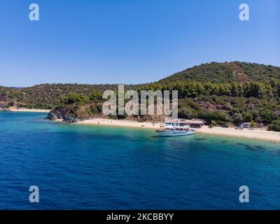 Luftpanorama aus der Vogelperspektive von einer Drohne des Aretes-Strandes, in der Gegend von Toroni, einem versteckten Juwel in Chalkidiki. Der Strand mit goldenem Sand und transparentem, kristallklarem smaragdgrünen Wasser, exotischem und tropischem Stil mit Pinien in der Nähe des Sandes, typisch für die Ägäis und das Mittelmeer, besteht aus 3 verschiedenen Buchten, wie sie von einigen Touristen gesehen wurden, die mit einem kleinen Schiff ankamen. Die Küste, die von felsigen Hügeln umgeben ist, ist ein versteckter Schatz für Einheimische und Touristen ohne die überfüllten Sommerszenen mit den Strandbars. Chalkidiki ist ein beliebtes Urlaubsziel, berühmt für die besten Strände in Stockfoto