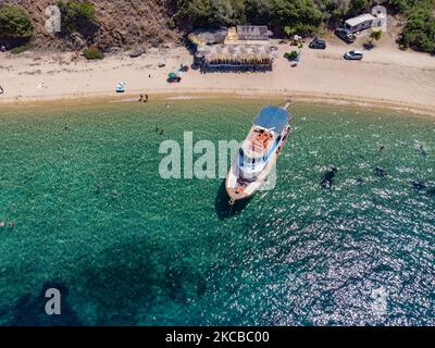 Luftpanorama aus der Vogelperspektive von einer Drohne des Aretes-Strandes, in der Gegend von Toroni, einem versteckten Juwel in Chalkidiki. Der Strand mit goldenem Sand und transparentem, kristallklarem smaragdgrünen Wasser, exotischem und tropischem Stil mit Pinien in der Nähe des Sandes, typisch für die Ägäis und das Mittelmeer, besteht aus 3 verschiedenen Buchten, wie sie von einigen Touristen gesehen wurden, die mit einem kleinen Schiff ankamen. Die Küste, die von felsigen Hügeln umgeben ist, ist ein versteckter Schatz für Einheimische und Touristen ohne die überfüllten Sommerszenen mit den Strandbars. Chalkidiki ist ein beliebtes Urlaubsziel, berühmt für die besten Strände in Stockfoto