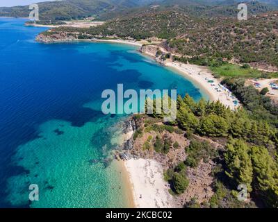 Luftpanorama aus der Vogelperspektive von einer Drohne des Aretes-Strandes, in der Gegend von Toroni, einem versteckten Juwel in Chalkidiki. Der Strand mit goldenem Sand und transparentem, kristallklarem smaragdgrünen Wasser, exotischem und tropischem Stil mit Pinien in der Nähe des Sandes, typisch für die Ägäis und das Mittelmeer, besteht aus 3 verschiedenen Buchten, wie sie von einigen Touristen gesehen wurden, die mit einem kleinen Schiff ankamen. Die Küste, die von felsigen Hügeln umgeben ist, ist ein versteckter Schatz für Einheimische und Touristen ohne die überfüllten Sommerszenen mit den Strandbars. Chalkidiki ist ein beliebtes Urlaubsziel, berühmt für die besten Strände in Stockfoto