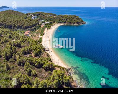Luftpanorama aus der Vogelperspektive von einer Drohne des Aretes-Strandes, in der Gegend von Toroni, einem versteckten Juwel in Chalkidiki. Der Strand mit goldenem Sand und transparentem, kristallklarem smaragdgrünen Wasser, exotischem und tropischem Stil mit Pinien in der Nähe des Sandes, typisch für die Ägäis und das Mittelmeer, besteht aus 3 verschiedenen Buchten, wie sie von einigen Touristen gesehen wurden, die mit einem kleinen Schiff ankamen. Die Küste, die von felsigen Hügeln umgeben ist, ist ein versteckter Schatz für Einheimische und Touristen ohne die überfüllten Sommerszenen mit den Strandbars. Chalkidiki ist ein beliebtes Urlaubsziel, berühmt für die besten Strände in Stockfoto
