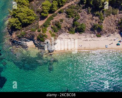 Luftpanorama aus der Vogelperspektive von einer Drohne des Aretes-Strandes, in der Gegend von Toroni, einem versteckten Juwel in Chalkidiki. Der Strand mit goldenem Sand und transparentem, kristallklarem smaragdgrünen Wasser, exotischem und tropischem Stil mit Pinien in der Nähe des Sandes, typisch für die Ägäis und das Mittelmeer, besteht aus 3 verschiedenen Buchten, wie sie von einigen Touristen gesehen wurden, die mit einem kleinen Schiff ankamen. Die Küste, die von felsigen Hügeln umgeben ist, ist ein versteckter Schatz für Einheimische und Touristen ohne die überfüllten Sommerszenen mit den Strandbars. Chalkidiki ist ein beliebtes Urlaubsziel, berühmt für die besten Strände in Stockfoto