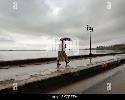 Ein Mann geht mit einem Regenschirm während der starken Regenfälle in Srinagar, dem indischen Kaschmir, am 24. März 2021. (Foto von Muzamil Mattoo/NurPhoto) Stockfoto