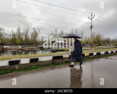 Ein Mann geht mit einem Regenschirm während der starken Regenfälle in Srinagar, dem indischen Kaschmir, am 24. März 2021. (Foto von Muzamil Mattoo/NurPhoto) Stockfoto