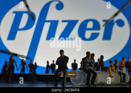 Medizinische Spritzen und kleine Figuren von Menschen sind vor dem Pfizer-Logo auf einem Bildschirm zu sehen. Am Samstag, den 26. März 2021, in Dublin, Irland. (Foto von Artur Widak/NurPhoto) Stockfoto