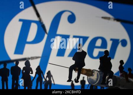 Medizinische Spritzen und kleine Figuren von Menschen sind vor dem Pfizer-Logo auf einem Bildschirm zu sehen. Am Samstag, den 26. März 2021, in Dublin, Irland. (Foto von Artur Widak/NurPhoto) Stockfoto