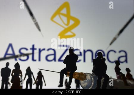 Medizinische Spritzen und kleine Figuren von Menschen sind vor dem AstraZeneca-Logo auf einem Bildschirm zu sehen. Am Samstag, den 26. März 2021, in Dublin, Irland. (Foto von Artur Widak/NurPhoto) Stockfoto