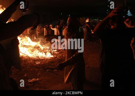 Während eines Rituals namens „Holika Dahan“, das im Rahmen der Holi-Feierlichkeiten an der Grenze zwischen Delhi und Uttar Pradesh in der Nähe von Ghazipur, am Stadtrand von Neu Delhi, stattfand, tanzen die Bauern, während sie Kopien der Agrargesetze in einem Lagerfeuer verbrennen. Indien am 28. März 2021. (Foto von Mayank Makhija/NurPhoto) Stockfoto