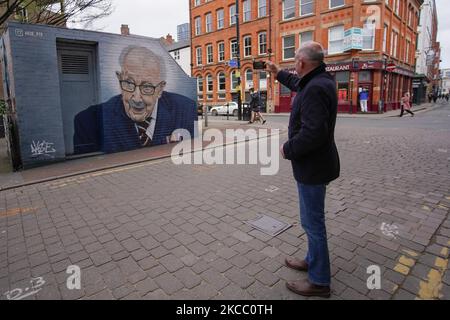 Ein Mann fotografiert ein Wandgemälde des Grafitti-Künstlers Akse P19, das Captain Sir Tom Moore in Zentral-Manchester zeigt. (Foto von Giannis Alexopoulos/NurPhoto) Stockfoto