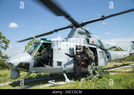 Eine US-Marine führt eine Familie an Bord eines UH-1Y-Hubschraubers während einer Hurrikan-Rettungsmission. Stockfoto