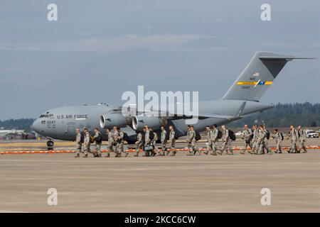Die Truppen entladen sich an Bord eines C-17 Globemaster III, während nach der Landung weitere C-17 Taxis einziehen. Stockfoto