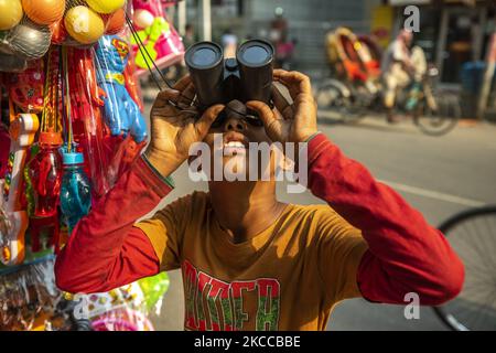 Am 06. April 2021 untersucht ein Straßenjunge ein Fernglas in Dhaka, Bangladesch. (Foto von Ahmed Salahuddin/NurPhoto) Stockfoto