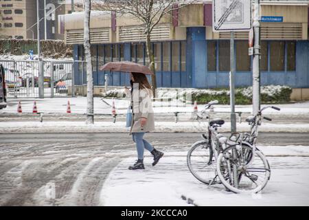 Eine junge Frau, die im Stadtzentrum von Eindhoven auf dem Schnee läuft und einen Regenschirm neben einigen Fahrrädern hält. Am dritten Tag des ungewöhnlichen Schneefalls im April in den Niederlanden wacht das Land nach einem intensiven morgendlichen Schneefall, ein bizarres Ereignis für den April, mit Schnee bedeckt auf. Die 3. Tage mit niedrigen Temperaturen und Schneefall in den Niederlanden nach dem „Weißen Ostermontag“ mit einem deutlichen Temperaturabfall, der nach Angaben der niederländischen Meteorologischen Agentur KNMI den Gefrierpunkt erreicht hat, wodurch der Ostermontag zu einem der kältesten Tage aller Zeiten mit niedrigen Temperaturen wurde. Zusätzlich zu Schnee, Hagel und hohem Spe Stockfoto