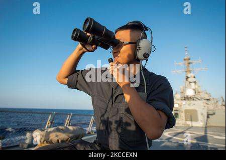 Seemann steht auf der USS Ross mit achterem Blick auf die Uhr. Stockfoto