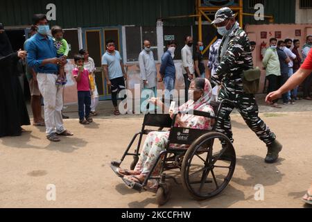 Eine ältere Wählerin wird von Einem paramilitärischen Personal unterstützt, nachdem sie während der Phase 4 der Parlamentswahlen in Westbengalen im Bezirk Howrah bei Kalkutta am 10. April 2021 ihre Stimme in einem Wahllokal abgegeben hat. (Foto von Debajyoti Chakraborty/NurPhoto) Stockfoto