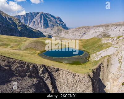 Panorama-Luftaufnahme einer Drohne des Drakolimni-Sees des Tymfi-Berges in der Nähe der Astraka- und Ploskos-Gipfel. Drakolimni bedeutet, dass Drago Lake der Name des sub-alpinen Sees im Nordwesten Griechenlands im Pindus-Gebirge in der Epirus-Region ist. Der See ist ein Wahrzeichen der Gegend, auf einer Höhe von 2050m. Über dem Meeresspiegel auf dem Bergmassiv von Timfi, im Vikos Aoos Nationalpark, ist der See eine 5-stündige Wanderung durch das Dorf Papingo, Es ist ein beliebtes Trekking-Ziel und wird von einer Art von alpinem Molch bewohnt. Drakolimni Tymfi, Griechenland am 2020. August (Foto: Nicolas Economou/NurPhot Stockfoto