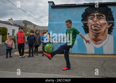 Johnny Figo Murphy, 9 Jahre alt, zeigt seine Fußballschuhe vor einem neuen Wandgemälde von CHELS (Chelsea Jacobs, ein in Dublin lebender amerikanischer Künstler), der Diego Maradona, einen der größten Spieler in der Geschichte des Fußballs, vertritt. Am Dienstag, den 13. April 2021, in Dublin, Irland. (Foto von Artur Widak/NurPhoto) Stockfoto