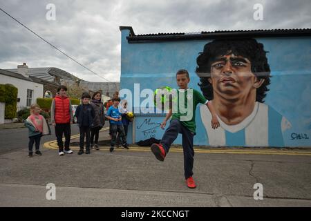 Johnny Figo Murphy, 9 Jahre alt, zeigt seine Fußballschuhe vor einem neuen Wandgemälde von CHELS (Chelsea Jacobs, ein in Dublin lebender amerikanischer Künstler), der Diego Maradona, einen der größten Spieler in der Geschichte des Fußballs, vertritt. Am Dienstag, den 13. April 2021, in Dublin, Irland. (Foto von Artur Widak/NurPhoto) Stockfoto