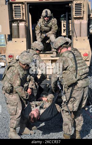 Soldaten der US-Armee üben das Heben eines verletzten Soldaten in den Rücken eines taktischen Fahrzeugs. Stockfoto