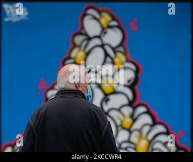 Ein Mann mit Gesichtsmaske kommt während der COVID-19-Sperre an einem Wandgemälde von Pens in Rathmines, Dublin, vorbei. Am Freitag, den 16. April 2021, in Dublin, Irland. (Foto von Artur Widak/NurPhoto) Stockfoto