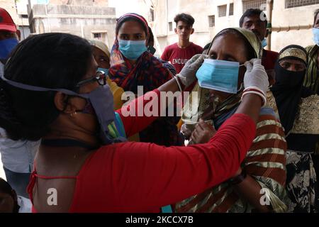 Gesundheitshelfer, die die chirurgische Gesichtsmaske auf den Wählern anschlagen, stehen vor dem Betreten eines Wahllokale, um während der Phase 5. der Parlamentswahlen in der West-Bengalen Nationalversammlung am 17. April 2021 in Kalkutta ihre Stimme abzugeben. (Foto von Debajyoti Chakraborty/NurPhoto) Stockfoto