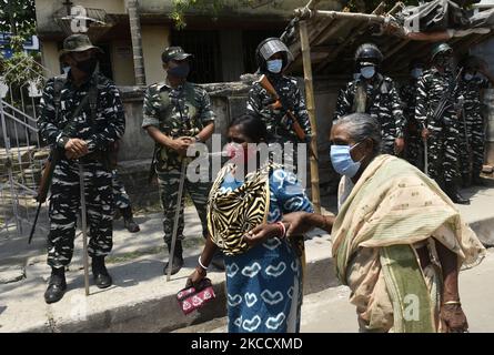 Ein paramilitärisches Personal steht und die Wähler stehen in einer Schlange, um ihre Stimme in einem Wahllokal während der fünften Phase der West Bengalen Parlamentswahlen in Kalkutta, Indien, am 17. April 2021 abzugeben. Laut einem indischen Medienbericht hat die Wahlkommission beschlossen, Kundgebungen, öffentliche Treffen und Straßenveranstaltungen in West-Bengalen von 7 bis 10 Uhr aufgrund der Covid-19-Spitze in Indien zu verbieten. (Foto von Indranil Aditya/NurPhoto) Stockfoto
