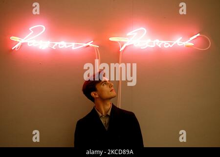 Ein Mitarbeiter posiert unter dem Neonlicht-Kunstwerk „Passion Passion“ des britischen Künstlers Tracey Emin, geschätzt auf GBP35.000-55.000, während einer Pressevorschau für den bevorstehenden Verkauf zeitgenössischer Kunst im Bonhams Auktionshaus in London, England, am 22. April 2021. Der Verkauf findet am 27. April statt. (Foto von David Cliff/NurPhoto) Stockfoto