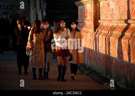 Eine Gruppe von Frauen mit Gesichtsmasken geht am 22. April 2021 bei Abendsonne in London, England, an der National Covid Memorial Wall of Hearts vorbei, wobei jedes Herz einen individuellen Coronavirus-Tod darstellt. (Foto von David Cliff/NurPhoto) Stockfoto