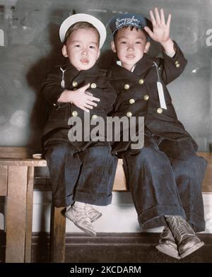 Zwei Japanisch-amerikanischen jungen warten auf einen Bus, der sie in ein Internierungslager, 1942. Stockfoto