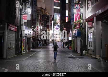 Eine junge Frau geht am 25. April 2021 auf der verlassenen Straße in der Innenstadt von Tokio, Japan, spazieren. (Foto von Yusuke Harada/NurPhoto) Stockfoto