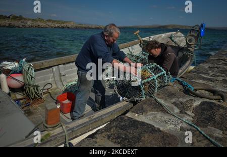 Der einheimische Fischer Michael John (links) und sein Nachbar Brendan Devane, abgebildet im Hafen von Ervallagh in der Nähe von Roundstone, bereiten ein Fischerboot für einen Angelausflug vor. Am Sonntag, 25. April 2021, in Ervallagh, Roundstone, Connemara, County Galway, Irland. (Foto von Artur Widak/NurPhoto) Stockfoto