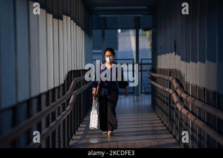 Eine Frau trägt Schutzmasken und geht am 26. April 2021 an der Fußgängerbrücke im Geschäftsviertel von Jakarta spazieren. Die Regierung der Provinz Jakarta hat die Öffentlichkeit aufgefordert, wachsam gegen die Übertragung von COVID-19 an den Arbeitsplätzen zu bleiben, da die Zahl der Beschäftigten, die dem Virus aus dem Büroverbund ausgesetzt waren, im April zugenommen hat. Die Zahl der aktiven Fälle aus dem Bürocluster erreichte am 12. Und 18. April 425 von 177 Arbeitsplätzen. Die meisten der gefundenen positiven Fälle waren von Arbeitsplätzen, die Impfungen erhalten haben. (Foto von Afriadi Hikmal/NurPhoto) Stockfoto