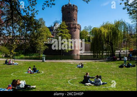 Die Menschen sitzen in Kreisen, die auf das Gras gemalt sind, während sie die Sonne im Park genießen, während der Feier zum Königstag während der Corona-Pandemie am 27. 2021. April in Nijmegen, Niederlande, Niederlande. (Foto von Romy Arroyo Fernandez/NurPhoto) Stockfoto